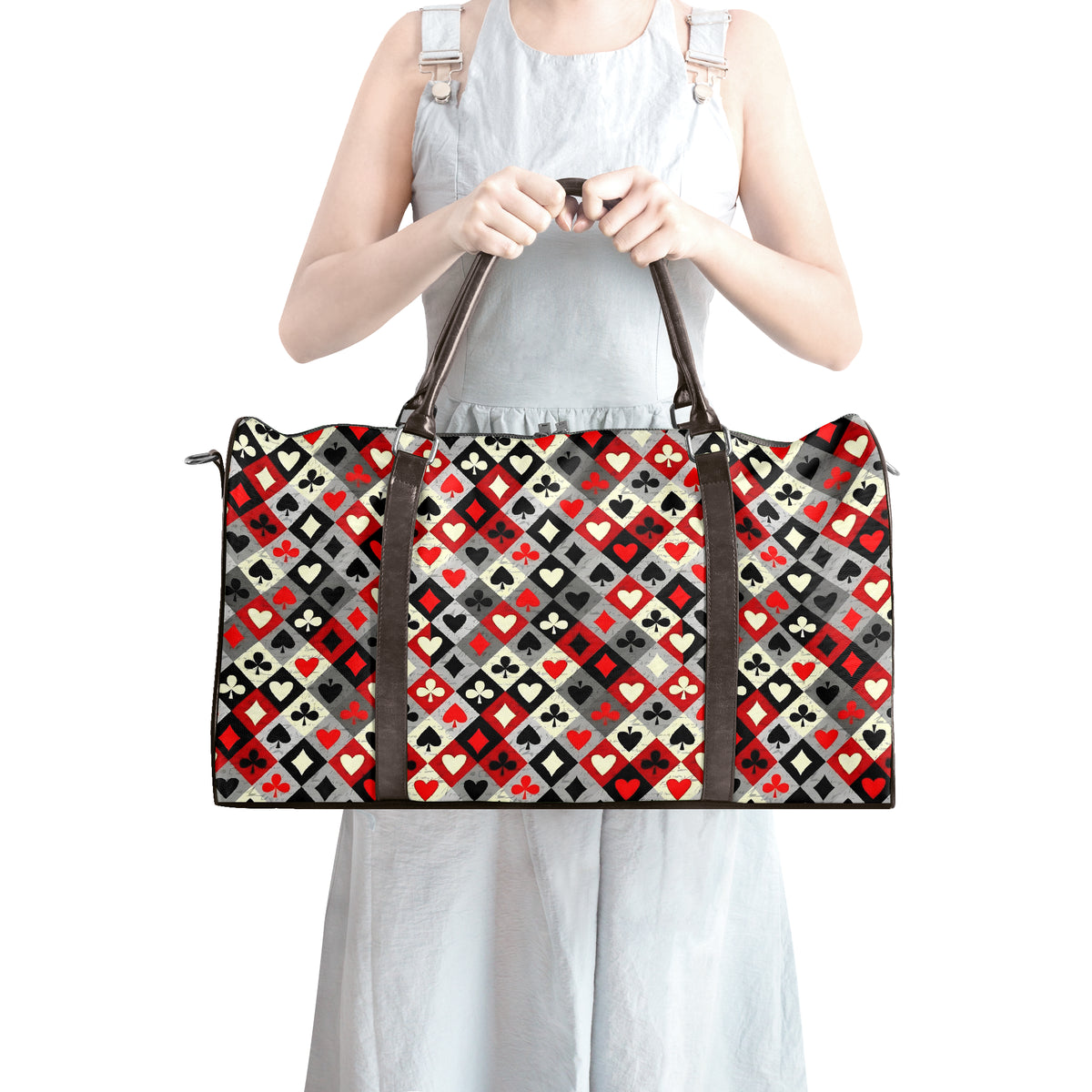 A woman in a light gray dress holds a large duffel bag with a geometric pattern of red, black, gray, and white playing card suits. The background is solid white.