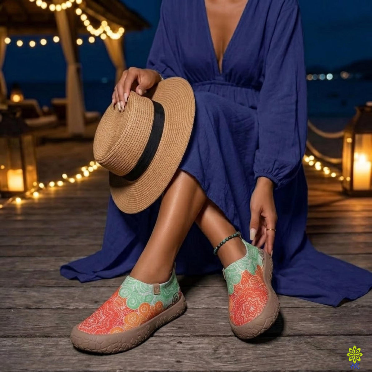 Scarpe slip-on a mandala indossate con un abito blu di sera accanto a lanterne, che mostrano la suola