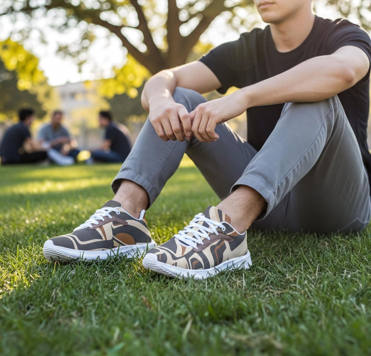 A person sitting on the grass wearing sneakers and a black shirt, with other people visible in the background.