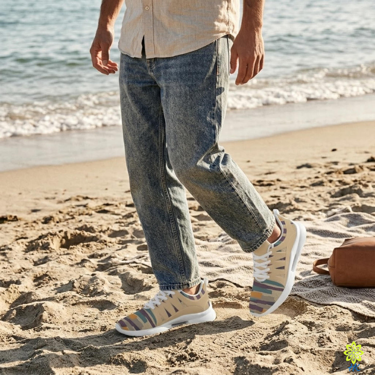 A person wearing jeans and colorful sneakers is walking on a sandy beach near the ocean.