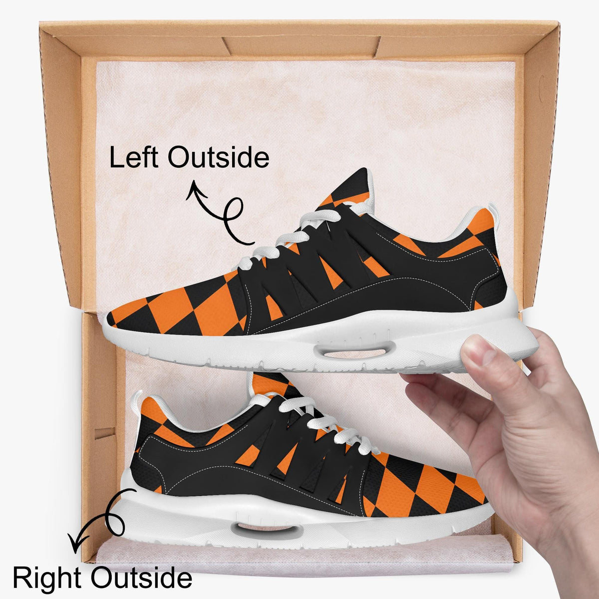 A hand is holding a pair of black and orange checkered sneakers, with the left shoe positioned outside the box and the right shoe inside the box.