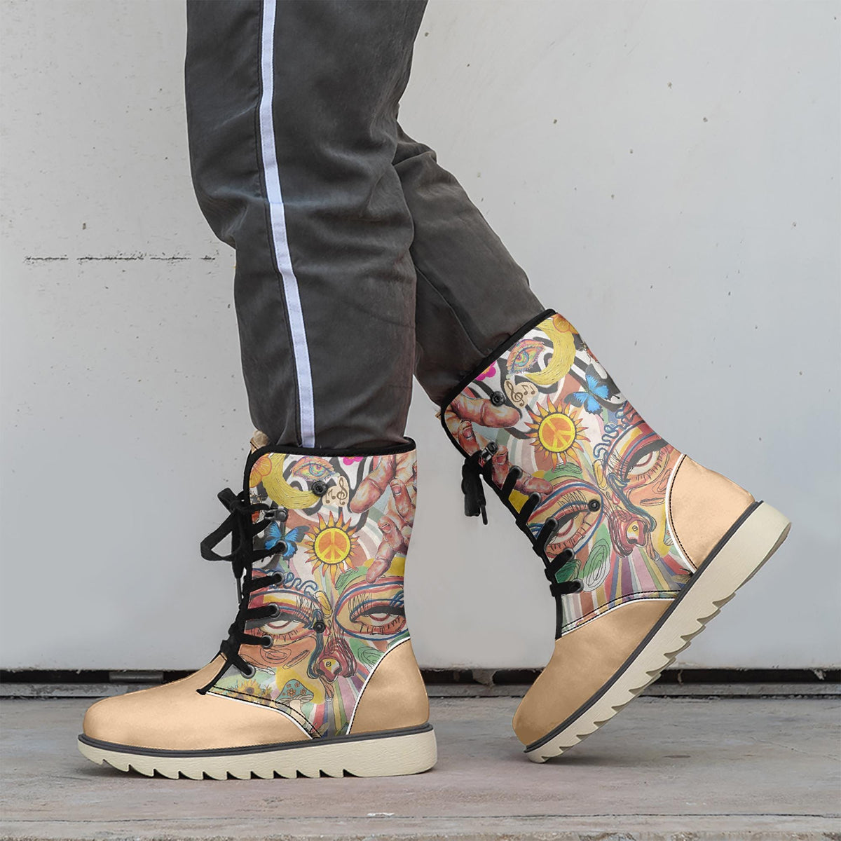 A person wearing colorful, patterned boots stands against a white wall.