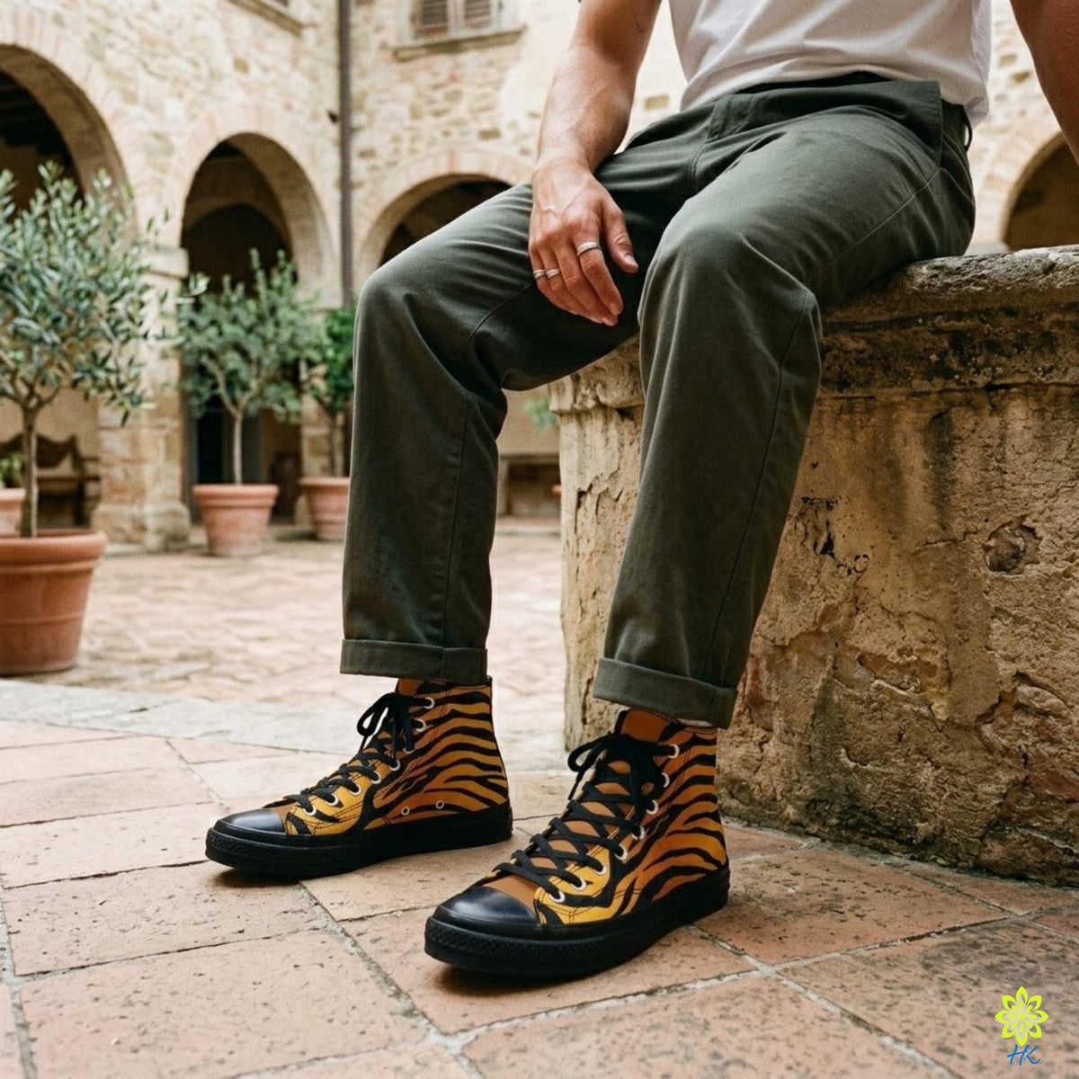 A person is sitting on a stone wall, wearing a pair of tiger-striped sneakers.