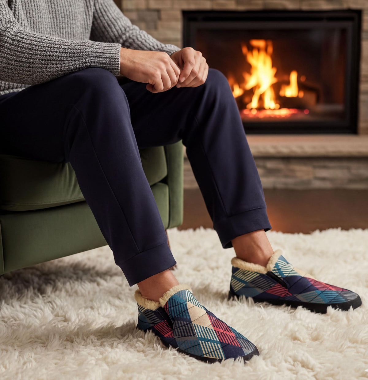 A person sitting in a chair in front of a fireplace, wearing patterned slippers.