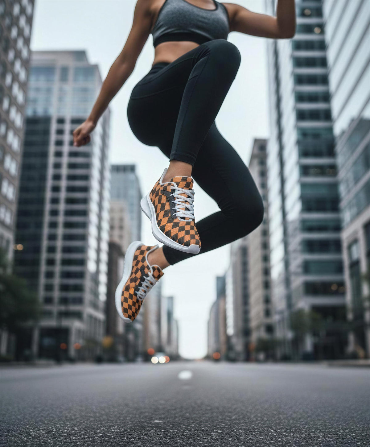 A person wearing black leggings and orange and black checkered sneakers is captured mid-jump in an urban setting with tall buildings in the background.