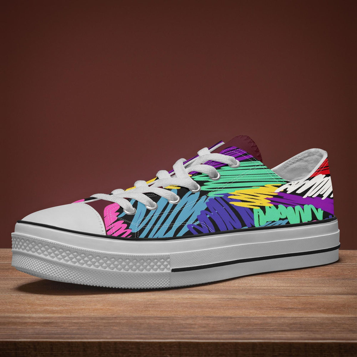 A colorful, patterned sneaker with a white sole and laces is displayed on a wooden surface against a red background.