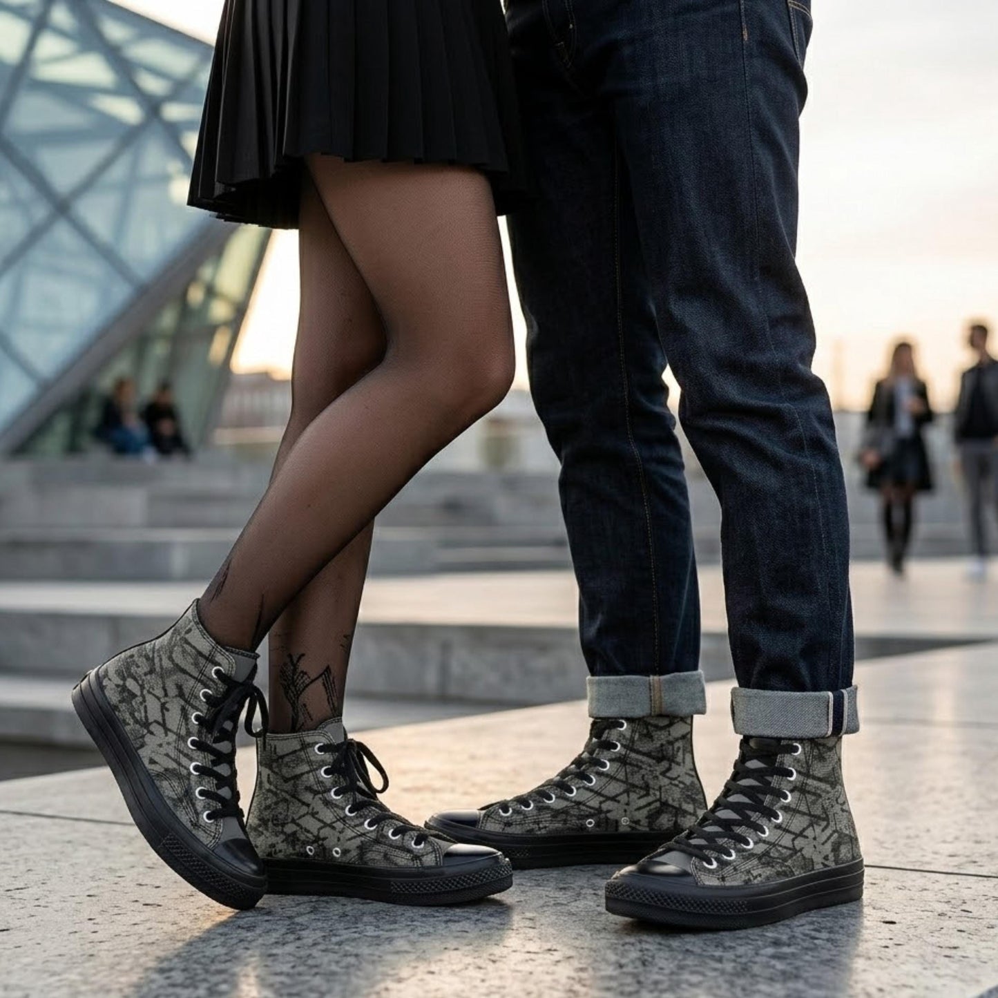 A couple standing close together, with the woman wearing high-top sneakers and the man wearing jeans.