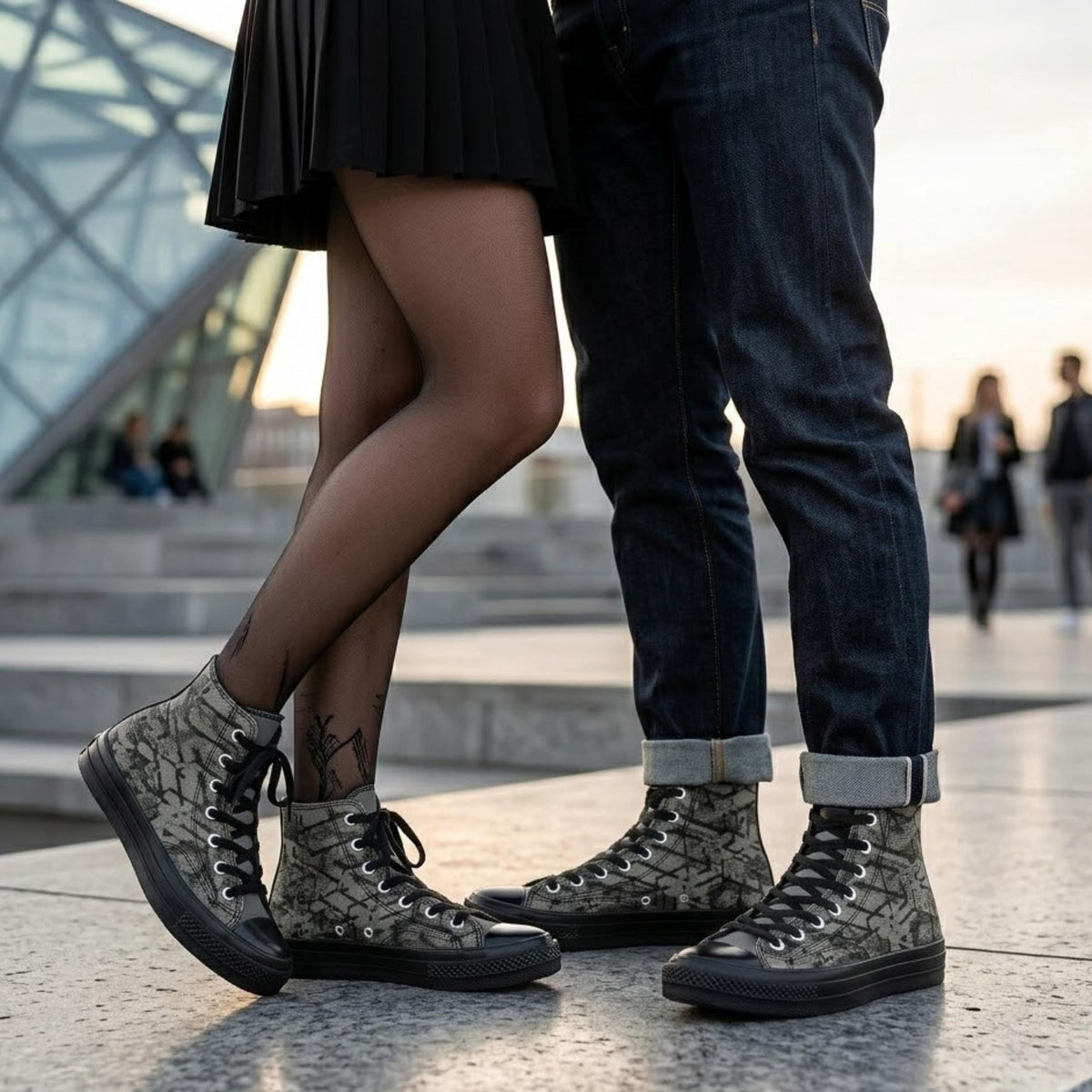 A couple standing close together, with the woman wearing high-top sneakers and the man wearing jeans.