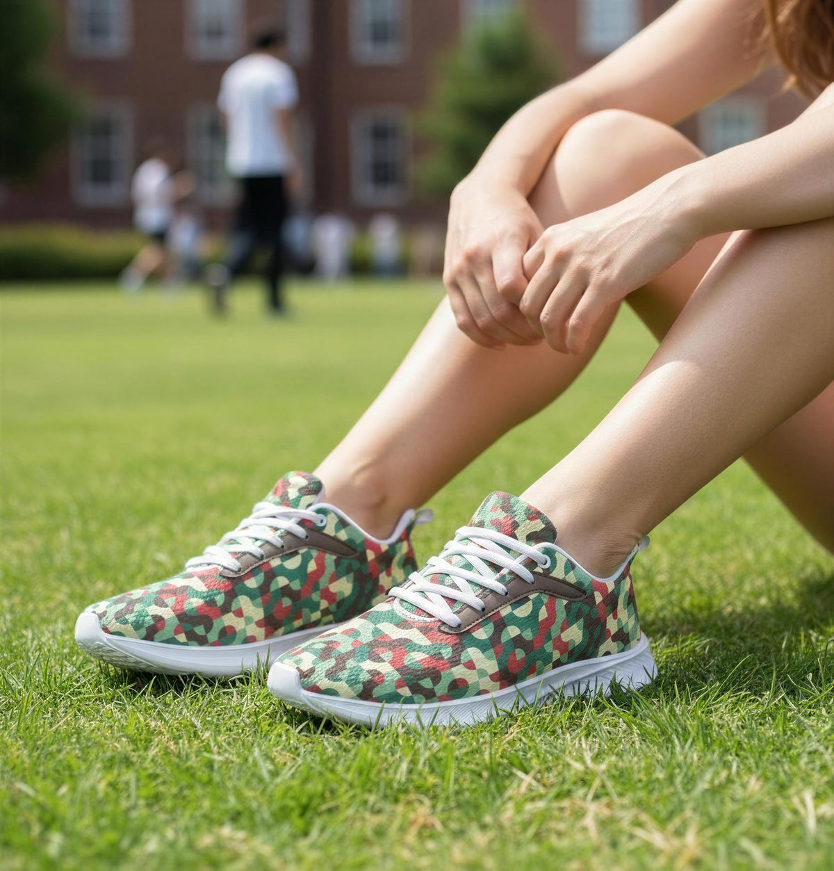A person sitting on the grass wearing camouflage sneakers.