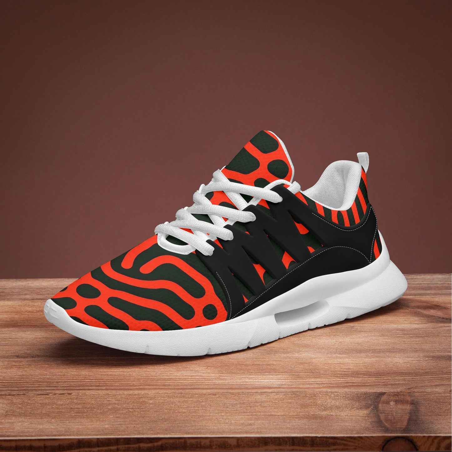 A colorful and patterned sneaker with a bold design of orange and black stripes on a wooden surface.