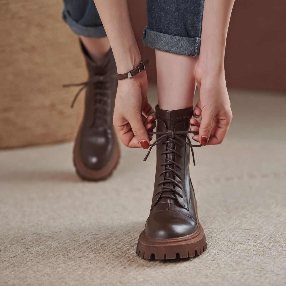 A person's feet wearing brown leather boots with laces, standing on a carpeted floor.