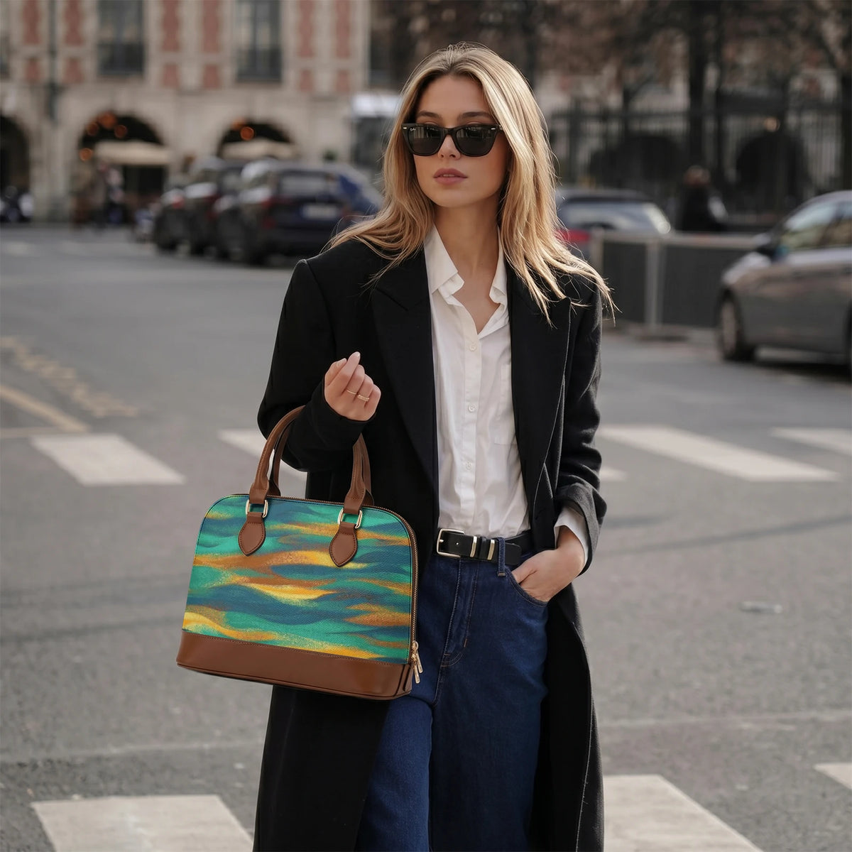 Donna con blazer nero che tiene la borsa astratta petrolio per il manico su una strada