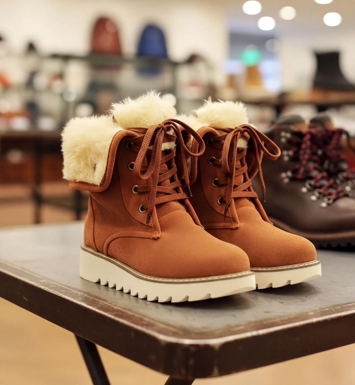 A pair of brown boots with white fur lining, displayed on a table in a store.