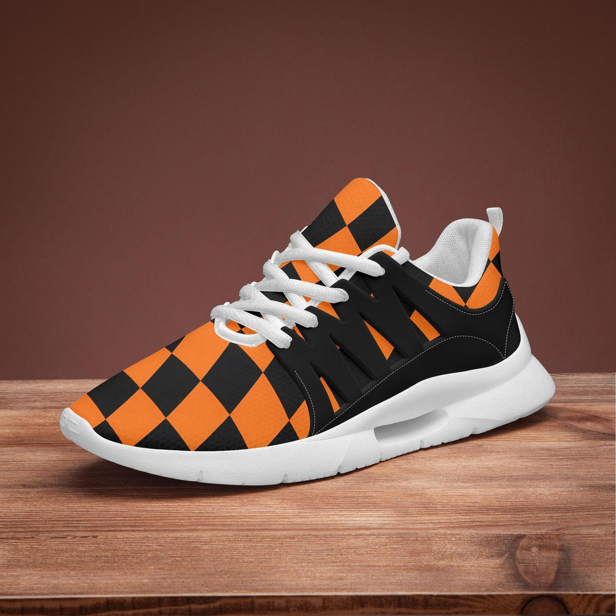 A black and orange checkered patterned sneaker is displayed on a wooden surface against a brown background.