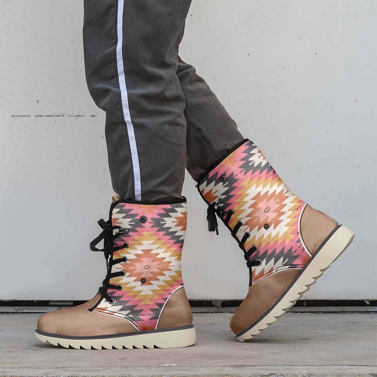 A person wearing colorful patterned boots stands against a white wall.