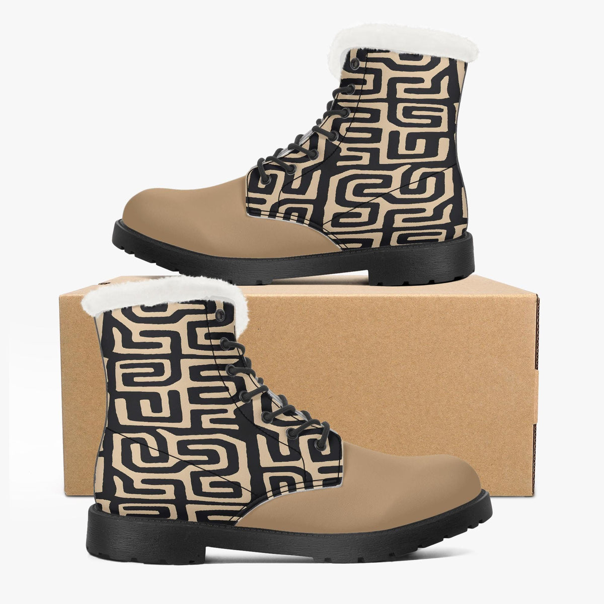A pair of tan boots with a black geometric pattern on the side, placed on top of a cardboard box.