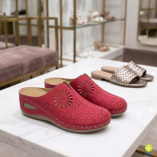 A pair of red, patterned slippers with a sunburst design, placed on a white marble countertop in a retail setting.