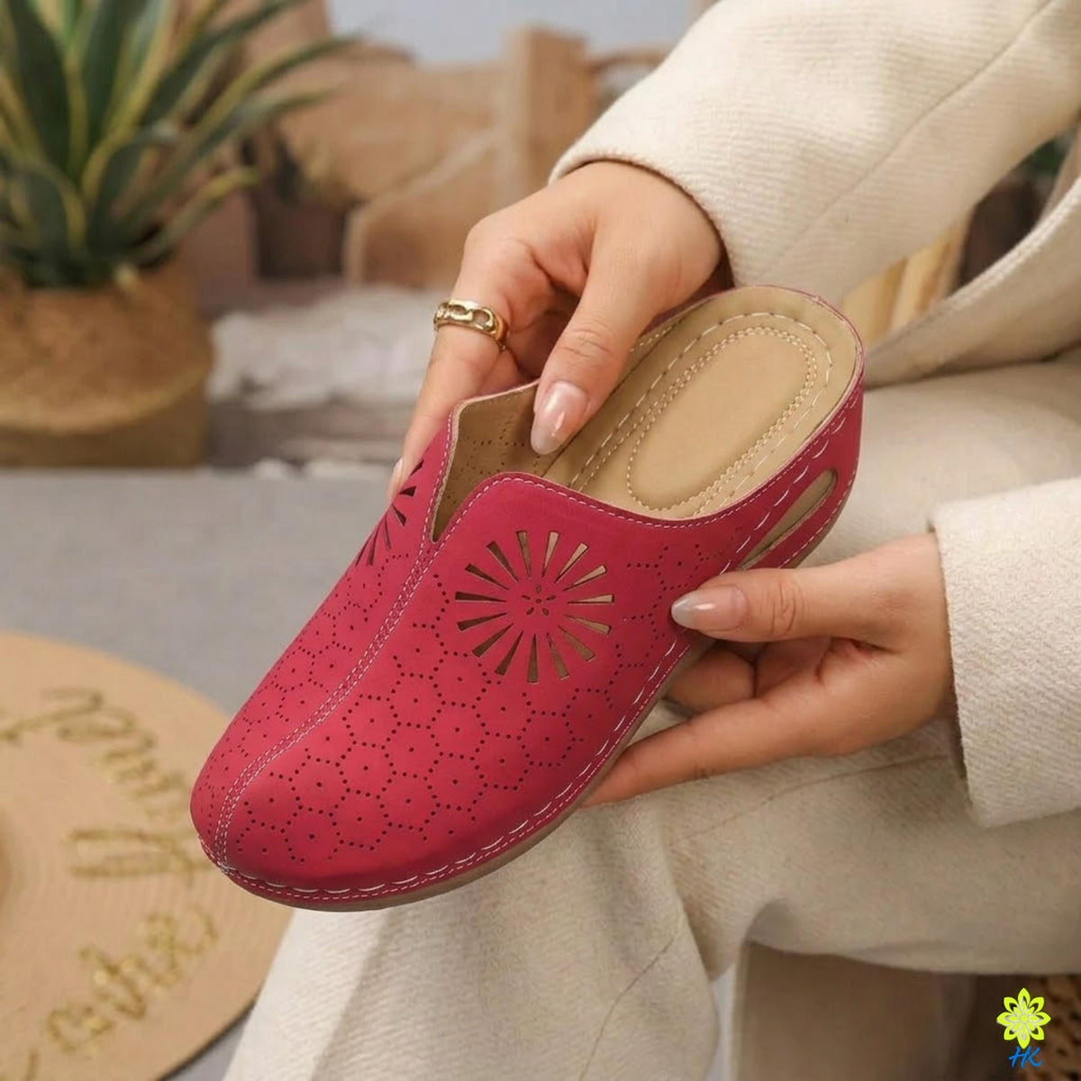 A person's hand holding a red, patterned shoe with a floral design.