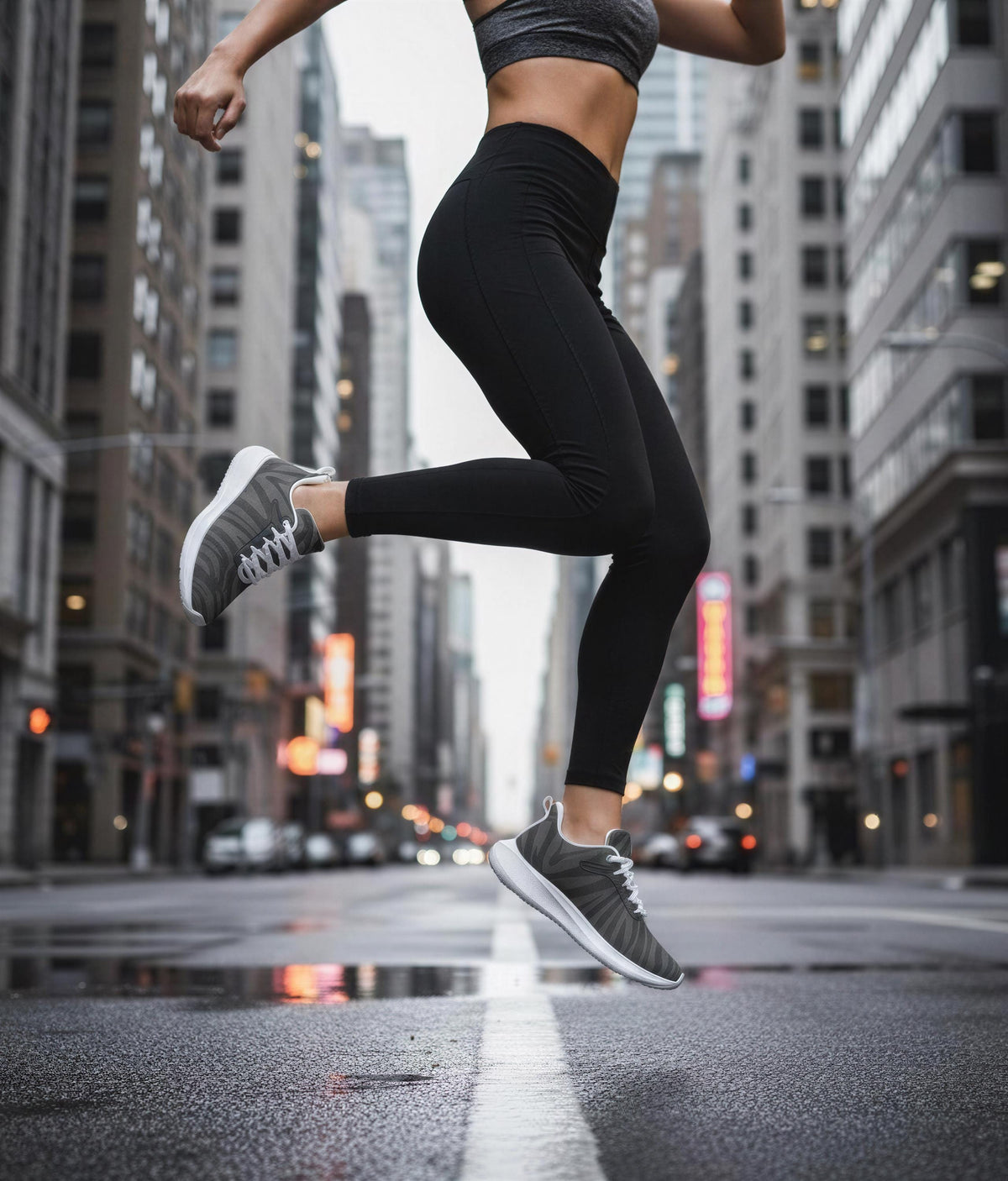 A woman in athletic clothing is captured mid-jump on a city street, with tall buildings and traffic lights in the background.