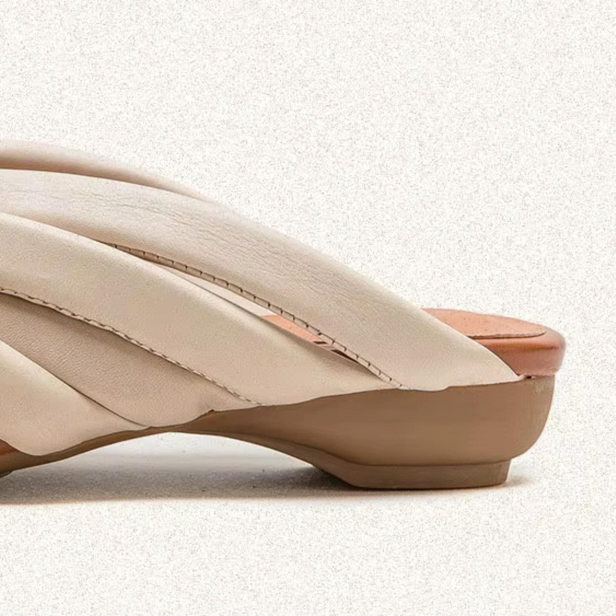 A close-up view of a beige leather shoe with a pointed toe and a strap across the top.