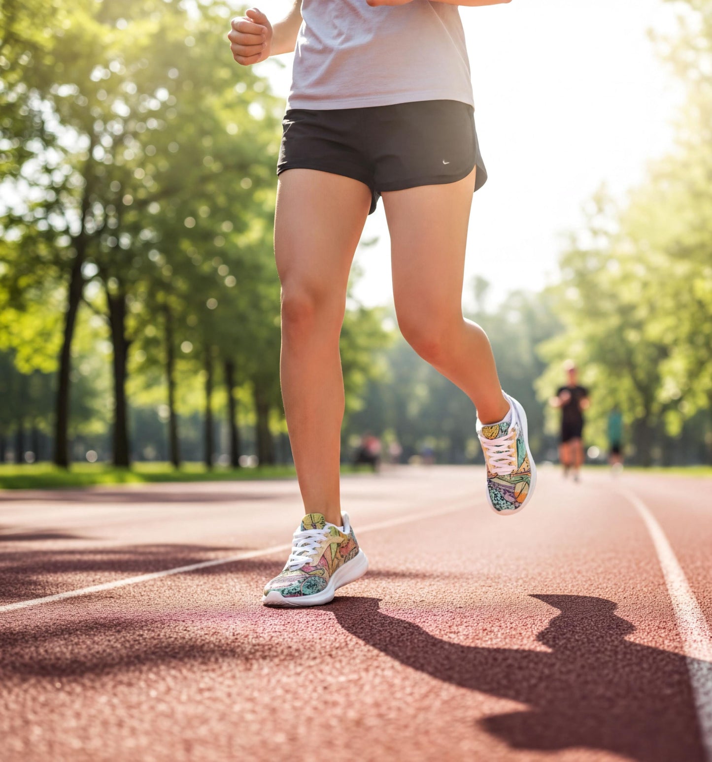 A person running on a track in a park, wearing colorful athletic shoes and shorts.