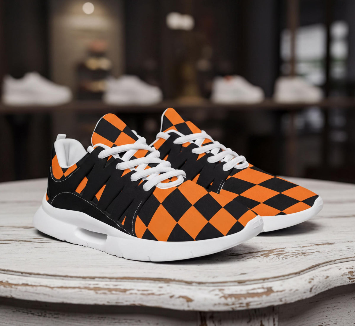A pair of orange and black checkered sneakers is displayed on a white wooden surface.