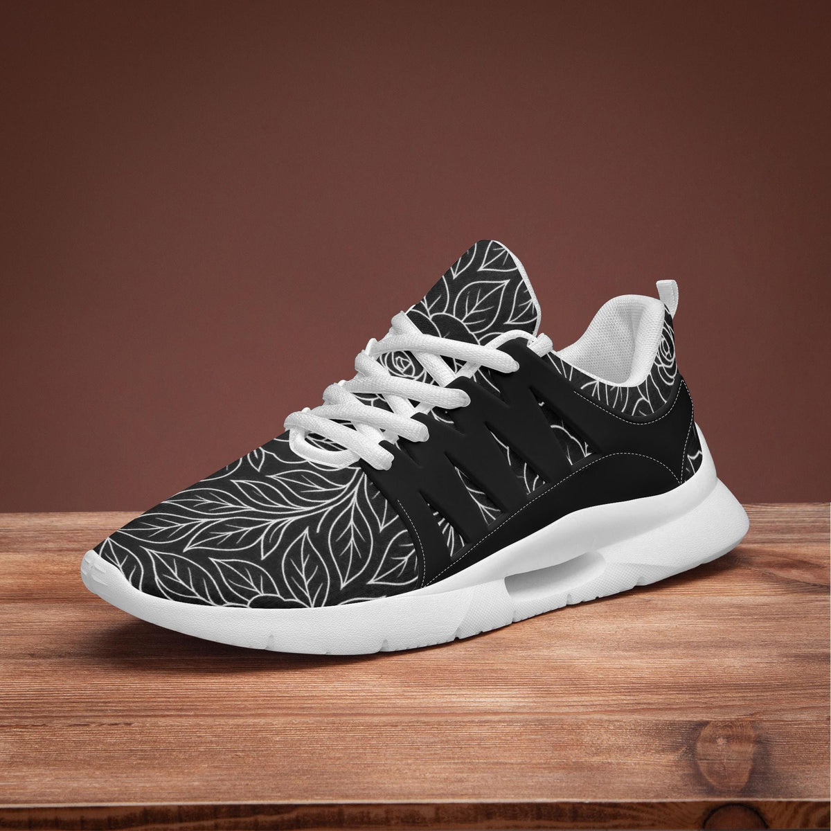A black and white patterned sneaker with white laces is displayed on a wooden surface against a brown background.