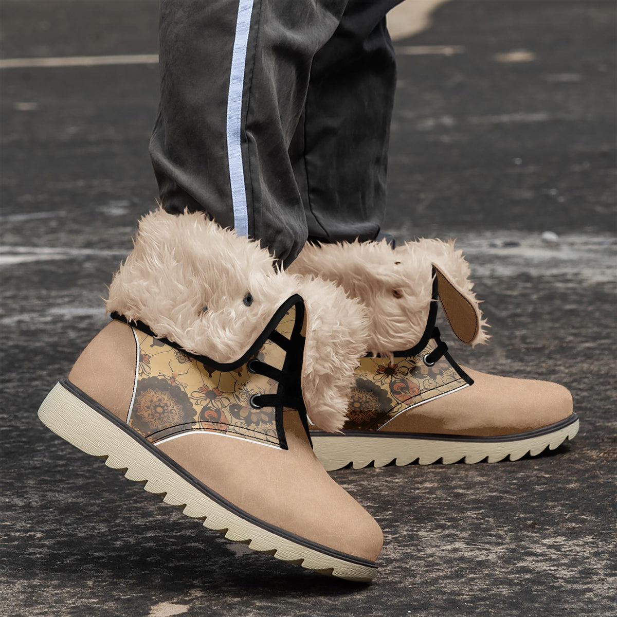 A pair of tan boots with fur trim and floral designs on the sides, standing on a black surface.