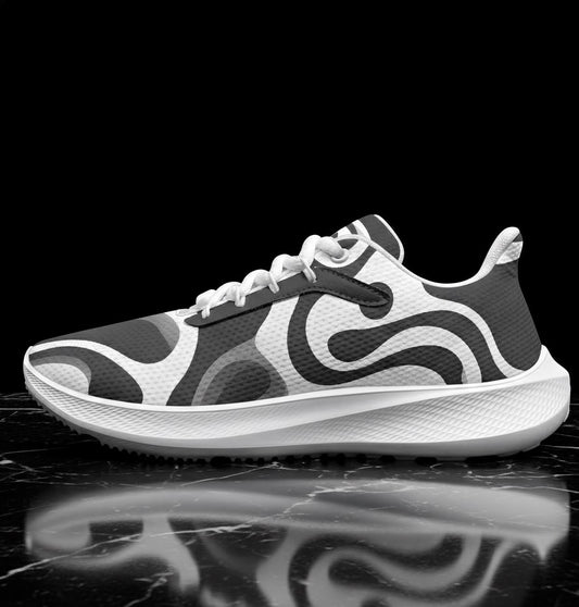 A black and white image of a white and gray athletic shoe with a distinctive swirly pattern on the side, displayed on a reflective surface.