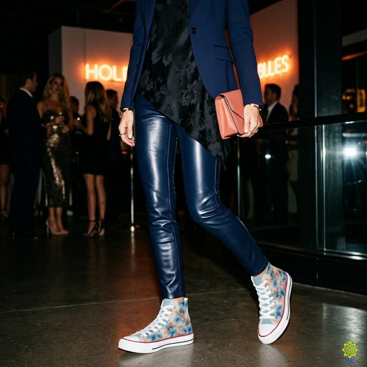Vrouw in marineblauwe blazer en broek met leerlook draagt bloemen canvas high-top sneakers op een avondevenement