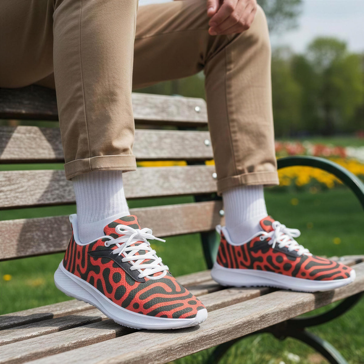 A person sitting on a wooden bench in a park, wearing patterned sneakers.
