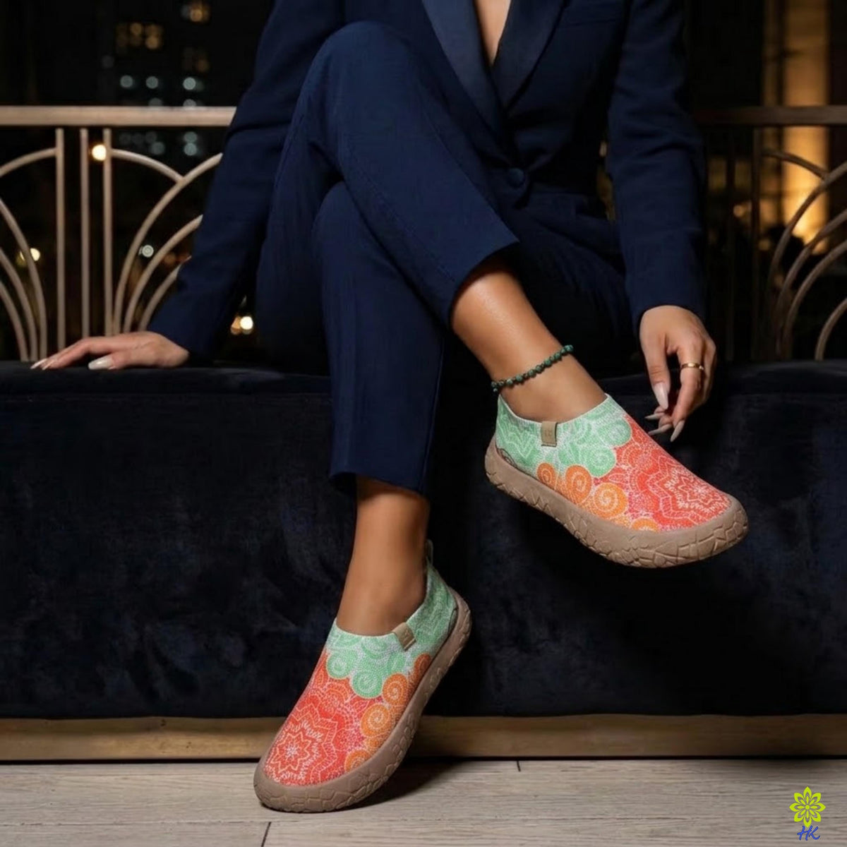Scarpe slip-on a mandala indossate con un abito blu navy mentre si è seduti su un divano di velluto