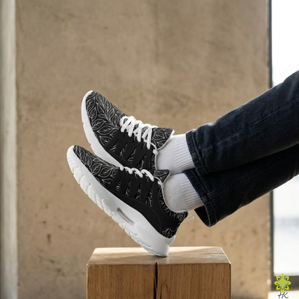 A pair of black and white sneakers with leaf patterns, placed on a wooden block.