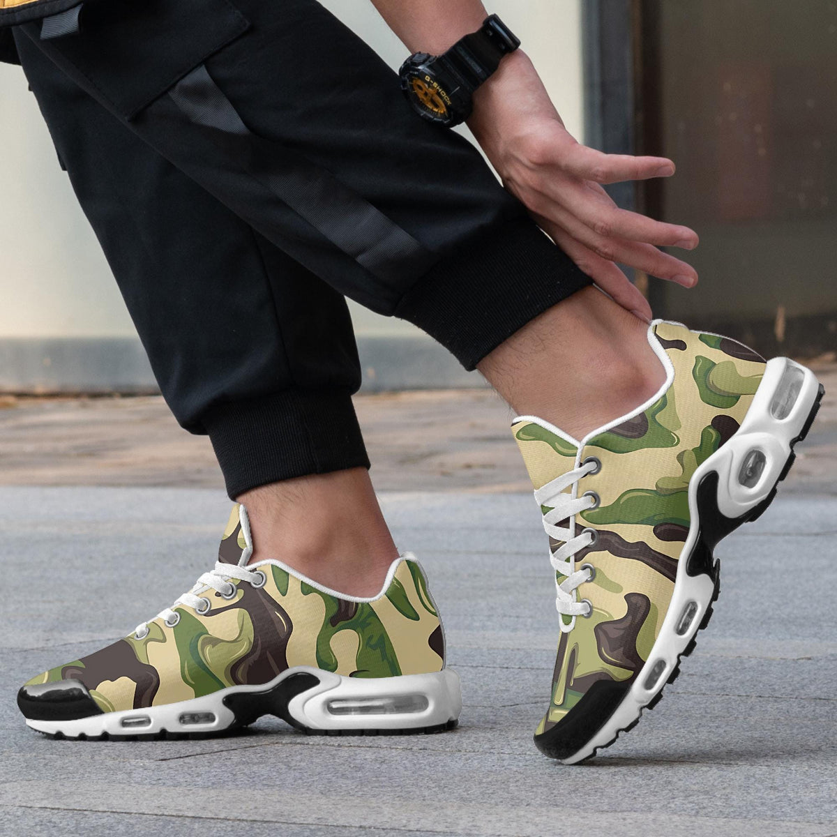 A person wearing camouflage-patterned sneakers is standing on a sidewalk, with their feet crossed and one foot in motion.