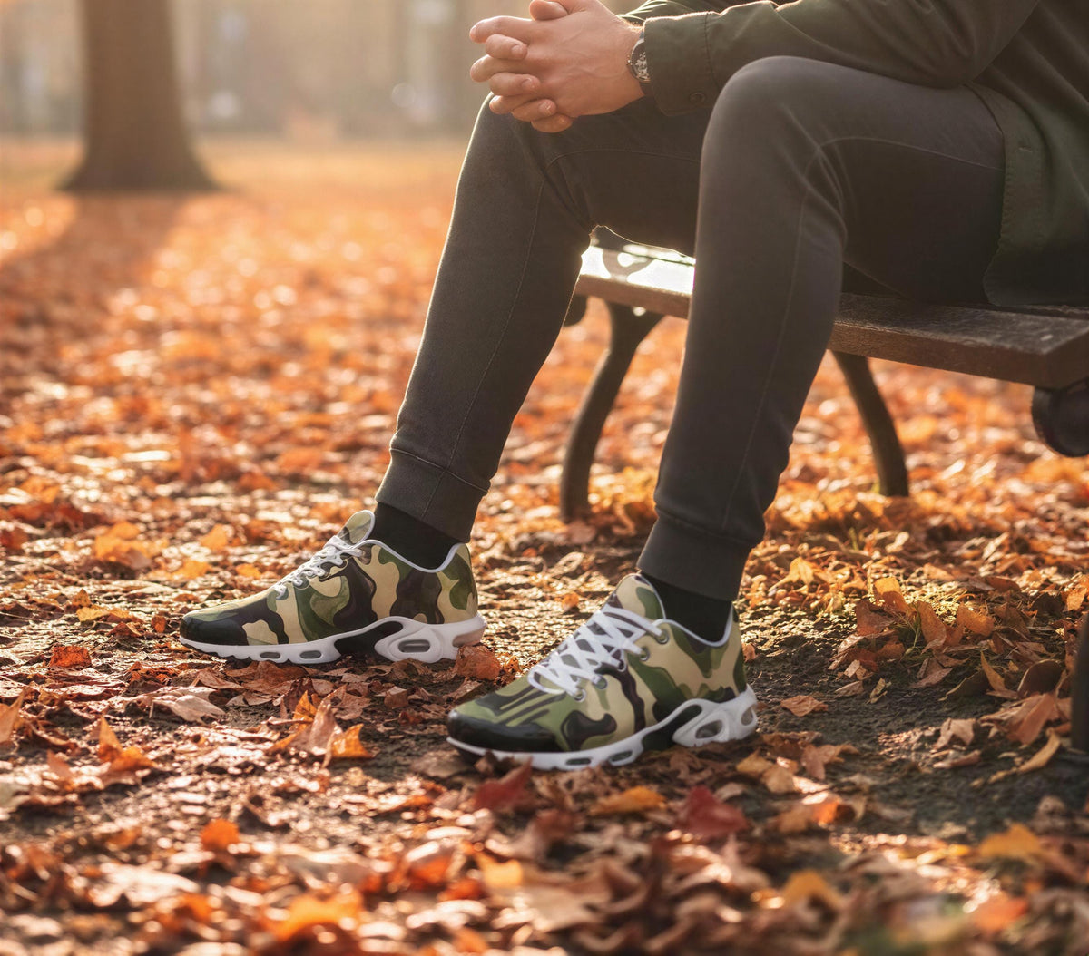 A person sitting on a bench in a park with autumn leaves on the ground.