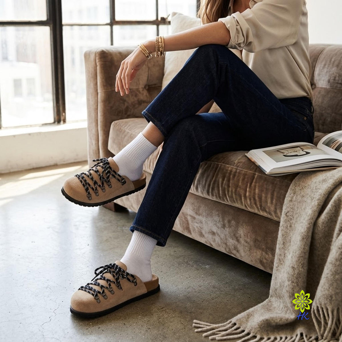 Model op een bank in jeans met gesloten lichtbruine muiltjes en witte accessoires