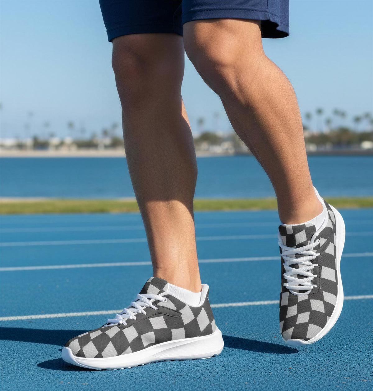 A person wearing black and white checkered sneakers is standing on a blue running track.