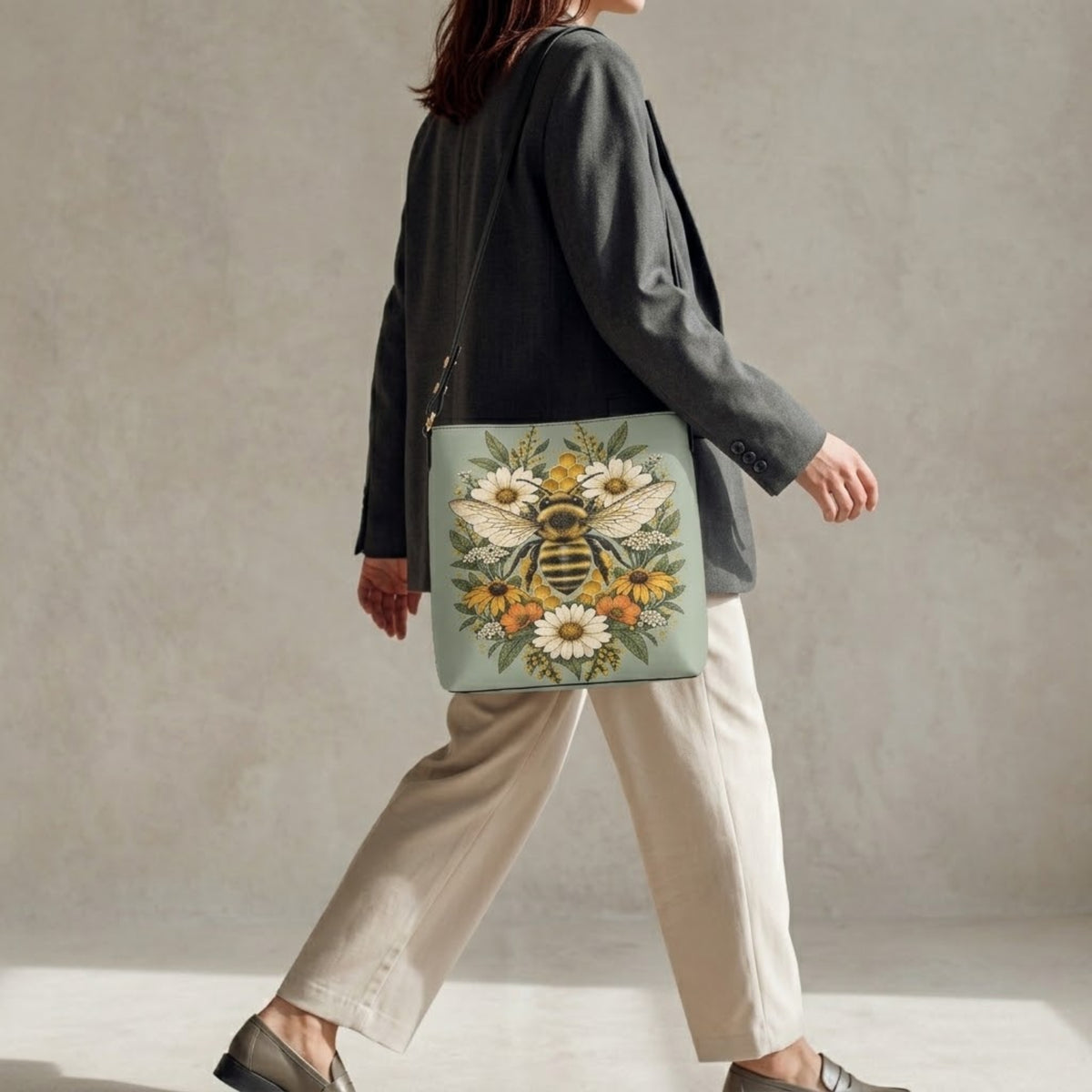 Mannequin marchant avec le sac porté épaule abeille sur l'épaule, associé à un blazer et un pantalon large