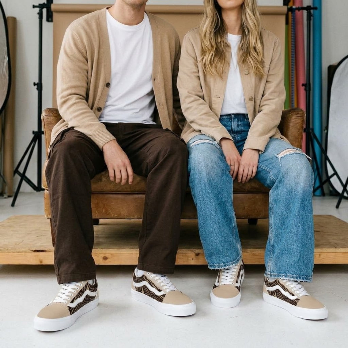 Deux mannequins assis sur un canapé portant des baskets en toile imprimé zèbre avec jean et pantalon