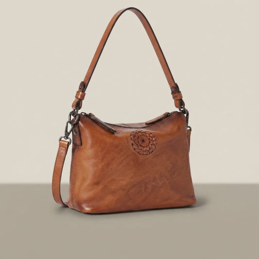 Front three-quarter view of a vintage leather crossbody bag in tan brown on a neutral background