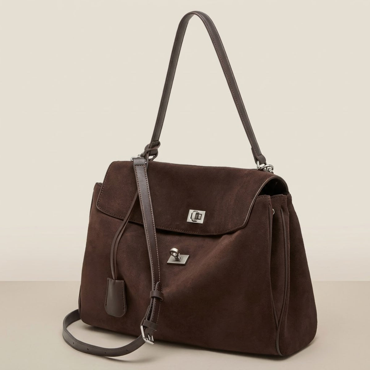 Model holding a black suede shoulder bag at her waist on a cafe street