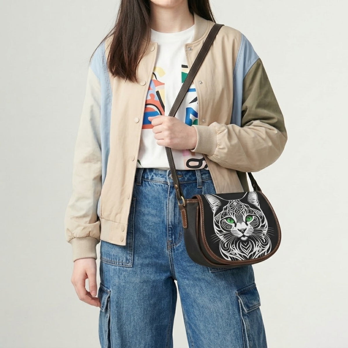 Model wearing cat crossbody bag over bomber jacket and jeans