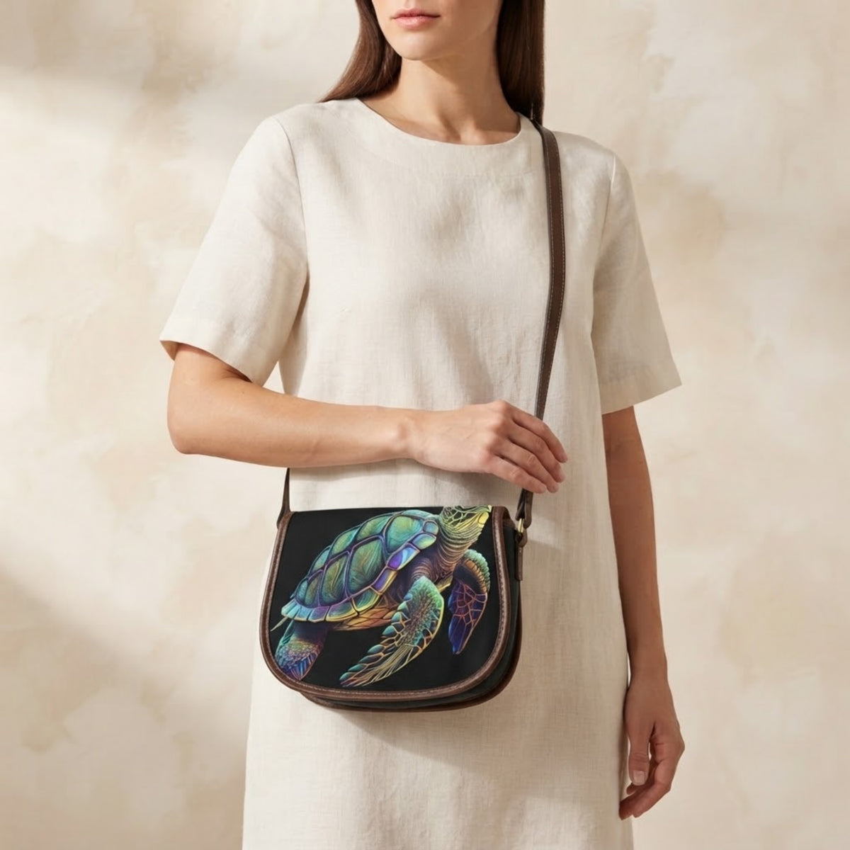 Modella che indossa la borsa a tracolla con tartarughe marine sulla spalla con un abito in lino color crema