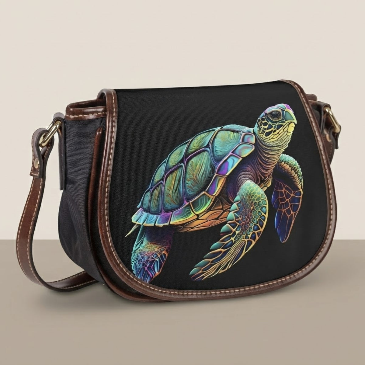 Borsa a tracolla saddle con tartarughe marine con patta in tela nera e opera di tartaruga stampata su sfondo bianco e beige