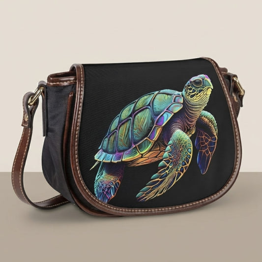 Borsa a tracolla saddle con tartarughe marine con patta in tela nera e opera di tartaruga stampata su sfondo bianco e beige