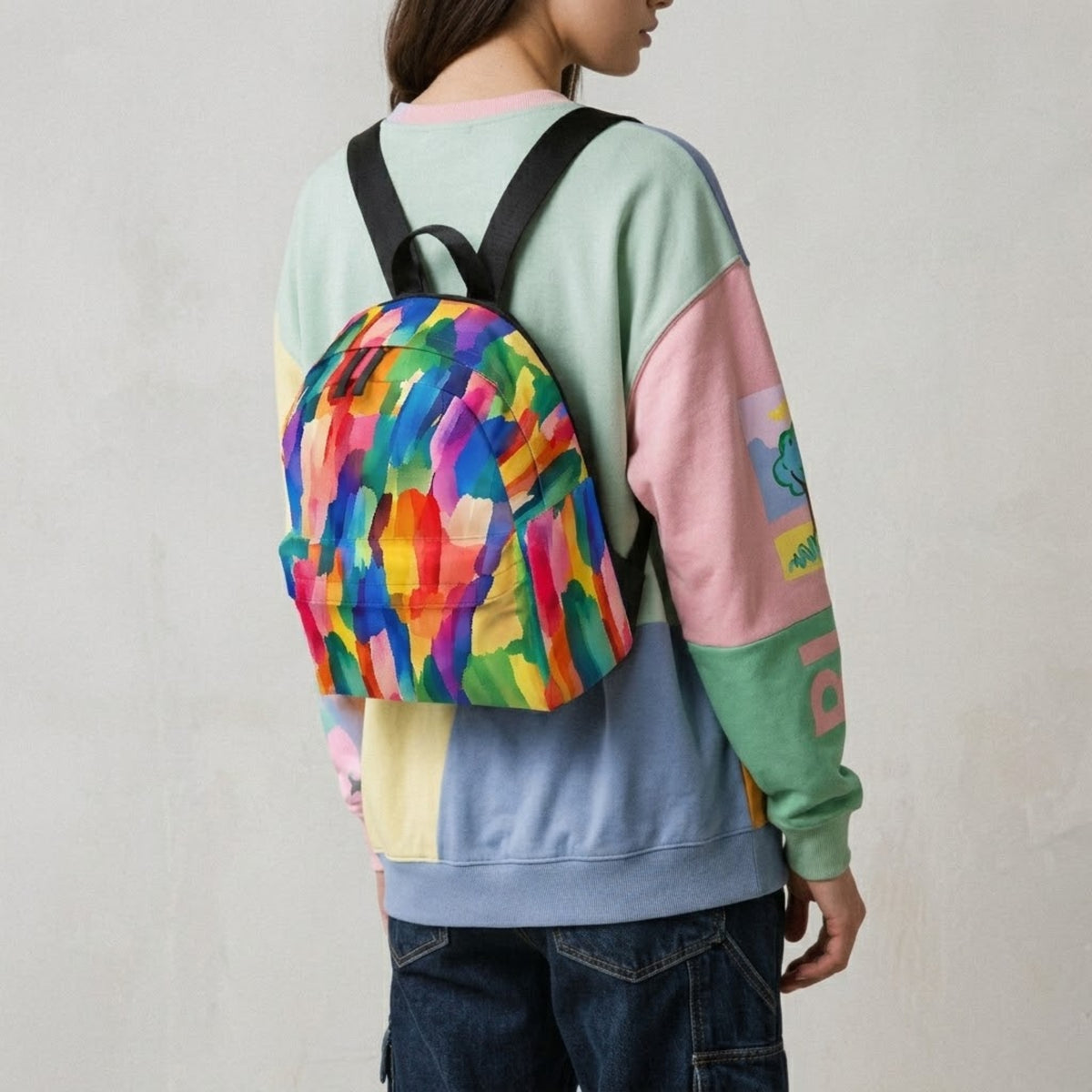 Woman wearing a colorful brushstroke backpack with a sweatshirt