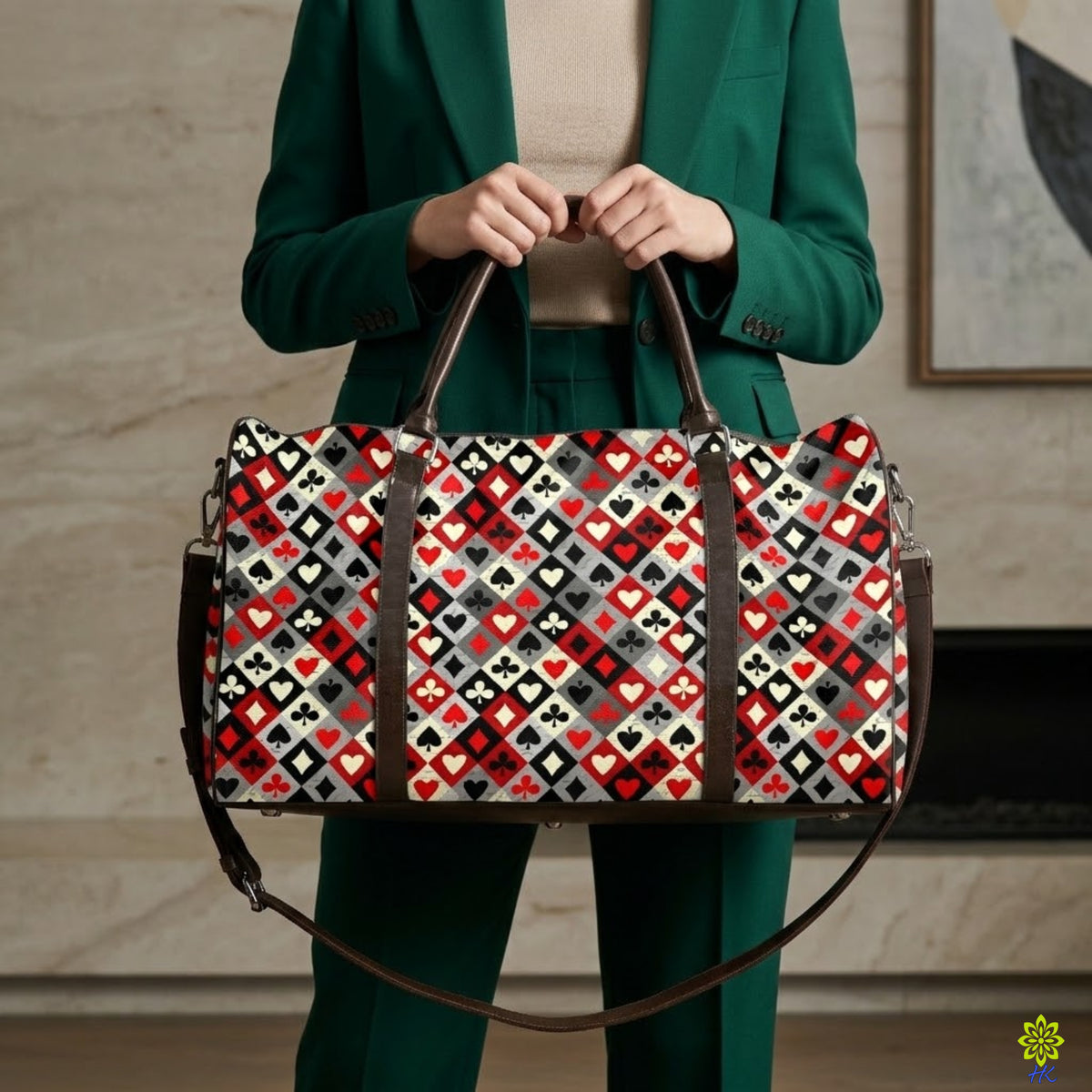 A person in a green blazer and matching pants holds a large duffel bag with a geometric diamond pattern in red, black, white, and gray, featuring dark brown handles and straps.