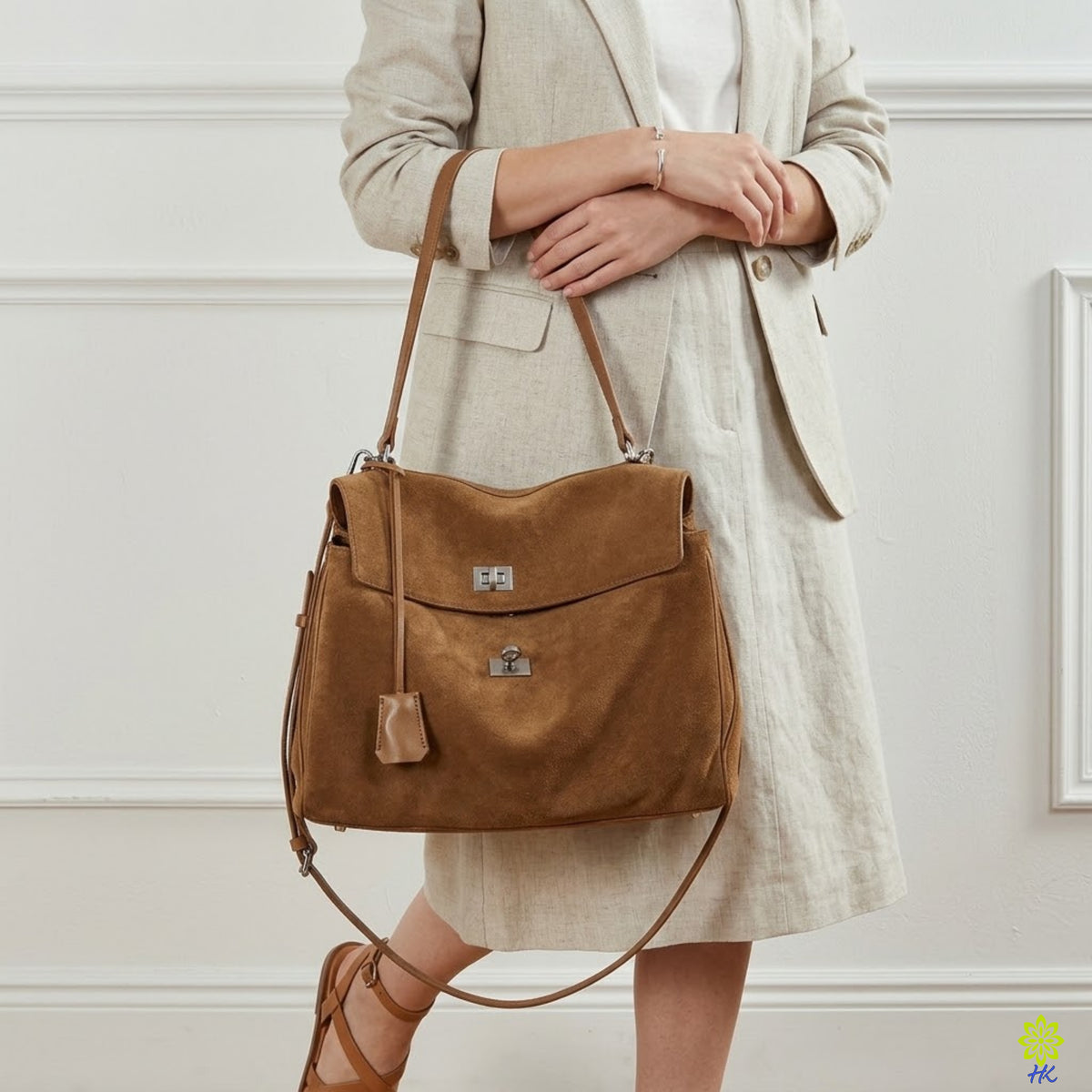 Model wearing a brown suede shoulder bag on her shoulder with a linen blazer