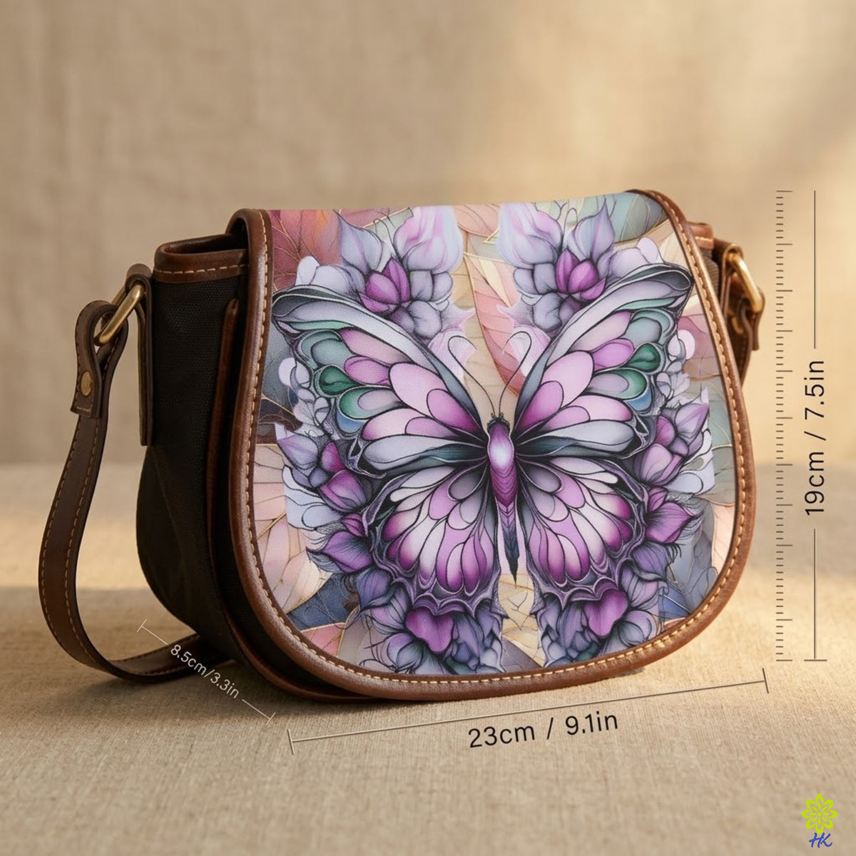 A handbag with a large colorful butterfly and floral print on the front flap, shown on a neutral beige surface with measurement lines and text indicating dimensions.