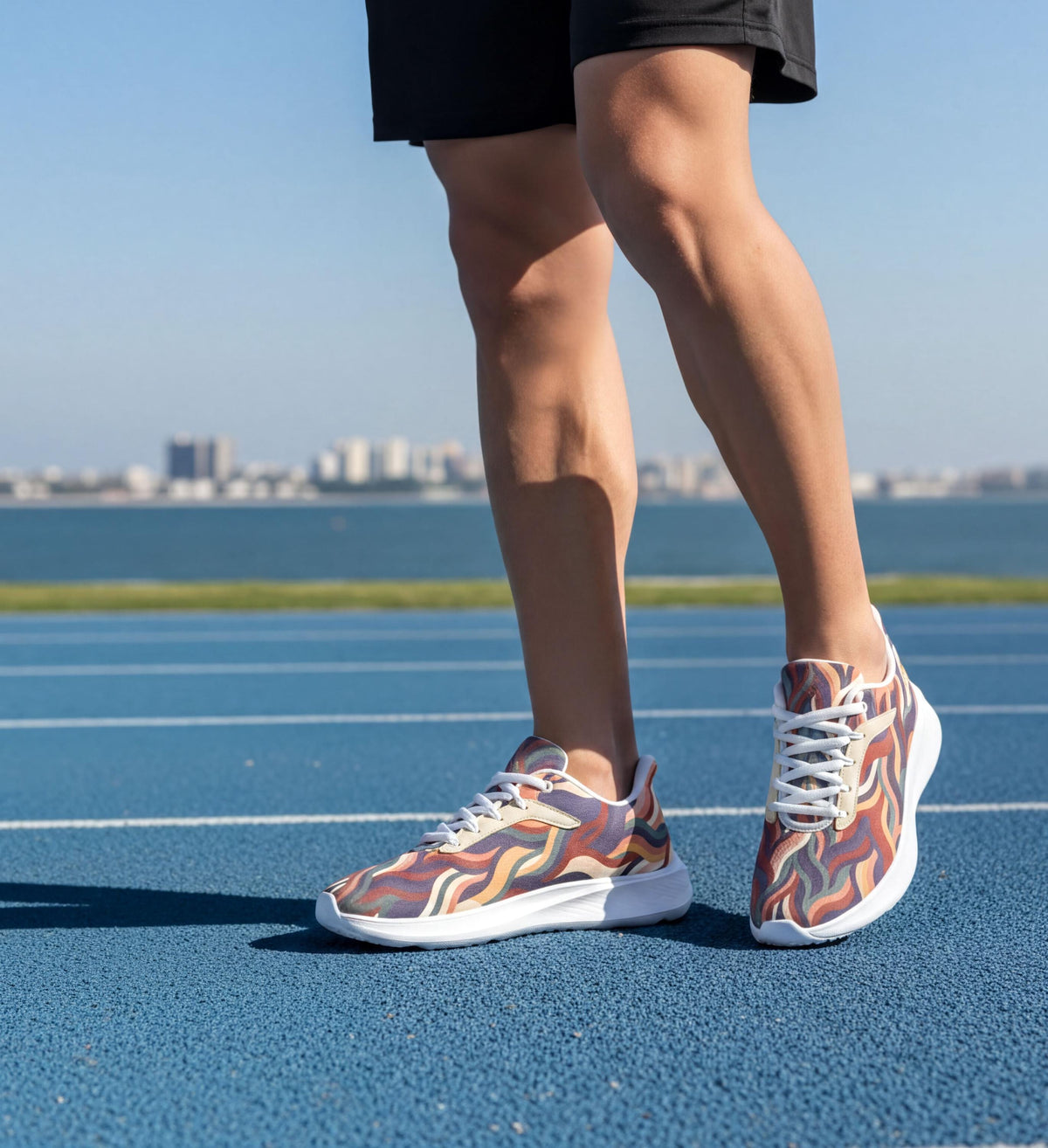 A person wearing colorful running shoes stands on a blue running track, with a city skyline visible in the background.